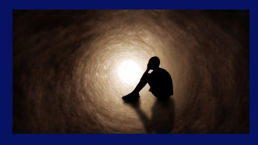 This illustration shows the silhouette of a young man sitting in a tunnel with his head in this hands, showing intense sadness.